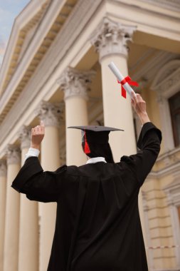Mezuniyet töreninden sonra dışarıda diplomalı bir öğrenci.