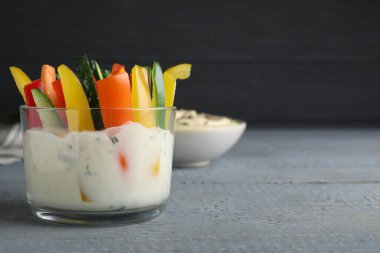 Gri ahşap masadaki soslu taze çiğ sebze çubukları. Metin için boşluk