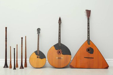 Beyaz duvarın yanında farklı ahşap müzik aletleri var.