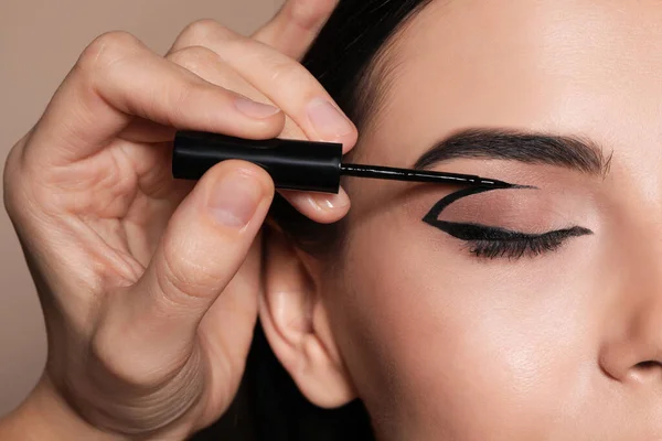 Artista Aplicando Delineador Preto Rosto Mulher Fundo Bege Close — Fotografia de Stock