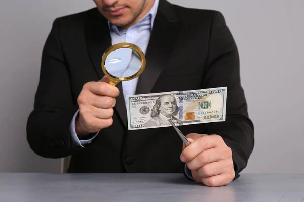 Açık Gri Arka Plandaki Masada Büyüteçle 100 Dolarlık Banknot Onaylama — Stok fotoğraf