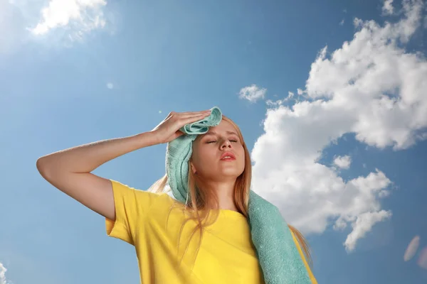 Woman with towel suffering from heat stroke outdoors