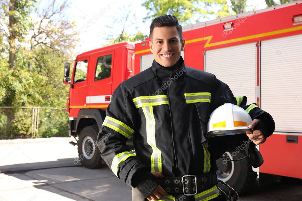 Portrait of firefighter in uniform with helmet near fire truck outdoors