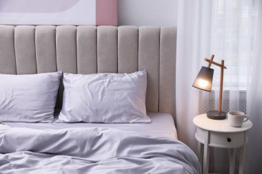 Işık odasında yumuşak ipek çarşaflı rahat bir yatak.