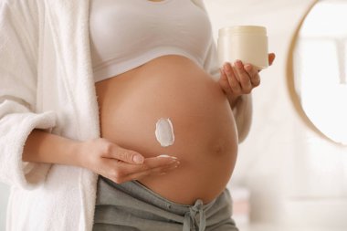 Banyoda kozmetik ürünüyle genç hamile kadın, yakın plan.