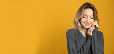 Sarı arka planda güzel sarı saçları ve büyüleyici gülüşü olan mutlu genç bir kadının portresi. Metin için boşluk