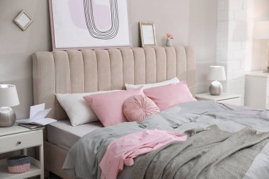 Gri duvarın yanında şık çarşaflı bir yatak.