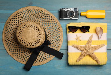 Açık mavi ahşap zemin üzerinde plaj nesneleri ile düz kompozisyon yatıyordu