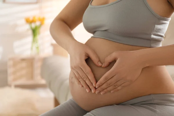 Zwangere Jonge Vrouw Maakt Hart Met Haar Handen Buik Thuis — Stockfoto