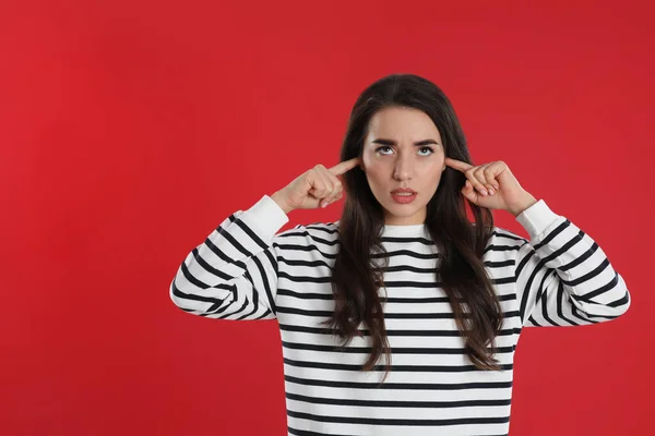 Jonge Vrouw Bedekken Oren Met Vingers Rode Achtergrond — Stockfoto