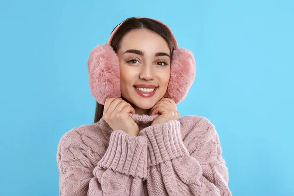 美しいです若いです女性身に着けていますEarmuff上のライトブルーの背景 — ストック写真