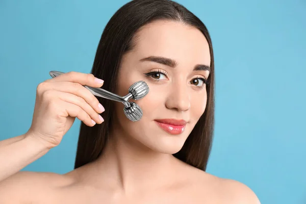 Mujer Usando Rodillo Facial Metal Sobre Fondo Gris Claro —  Fotos de Stock