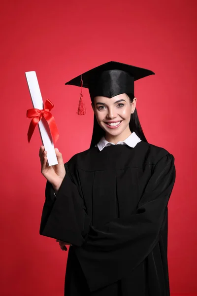 戴着红色背景的毕业帽和毕业文凭的快乐学生 — 图库照片