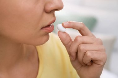 Bulanık arka planda kürtaj hapı alan genç kadın, yakın plan.