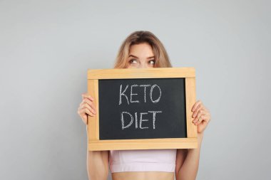 Gri arkaplanda Keto Diyetli karatahta tutan kadın