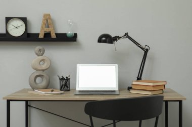 Açık gri duvarın yanındaki modern dizüstü bilgisayarı olan rahat bir iş yeri.