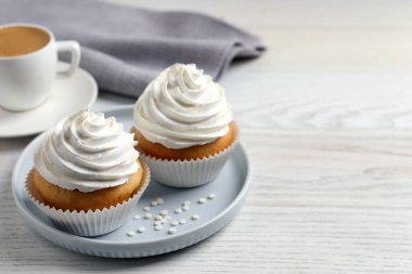 Kremalı lezzetli kekler ve beyaz ahşap masada bir fincan kahve. Metin için boşluk