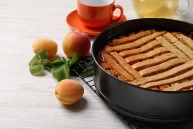 Pişirme kabında nefis kayısı turtası ve beyaz ahşap masada taze meyveler, yakın plan.