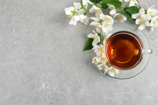 Szklana Filiżanka Aromatycznej Herbaty Jaśminowej Świeże Kwiaty Szarym Stole Płaskie — Zdjęcie stockowe