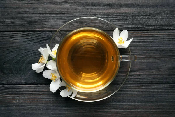 Glass Cup Aromatic Jasmine Tea Fresh Flowers Black Wooden Table — Fotografia de Stock