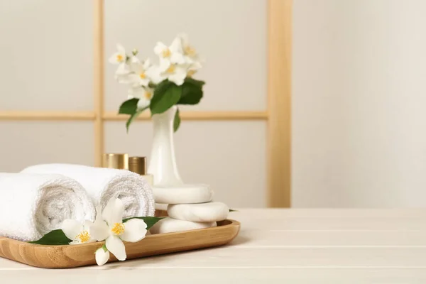 白色木制桌子上美丽的茉莉花 毛巾和矿泉石 文字空间 — 图库照片