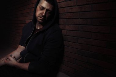 Aşırı dozda uyuşturucu bağımlısı adam tuğla duvarın yanında. Metin için boşluk