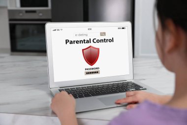 Küçük bir kız, mutfaktaki dizüstü bilgisayarda ebeveyn kontrolüne erişemiyor, yakın plan. Çocuk güvenliği