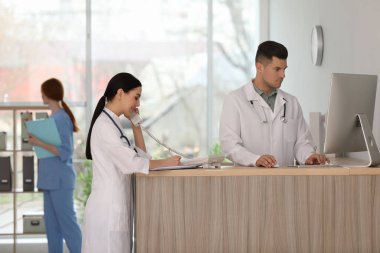 Hastanede tezgahta çalışan resepsiyonist ve doktor.