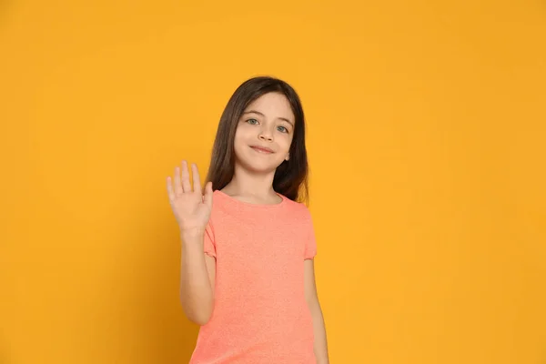 Menina Feliz Acenando Para Dizer Olá Fundo Amarelo — Fotografia de Stock