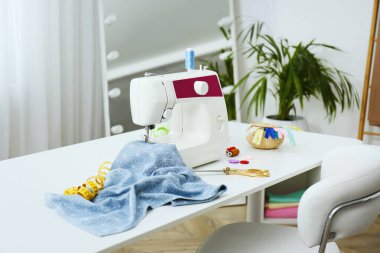 Modern dikiş makinesi, kumaş ve aksesuarlar masa içinde.