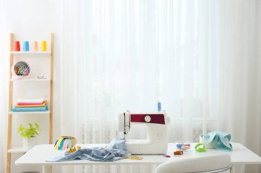 Modern dikiş makinesi, kumaş ve aksesuarlar masa içinde.