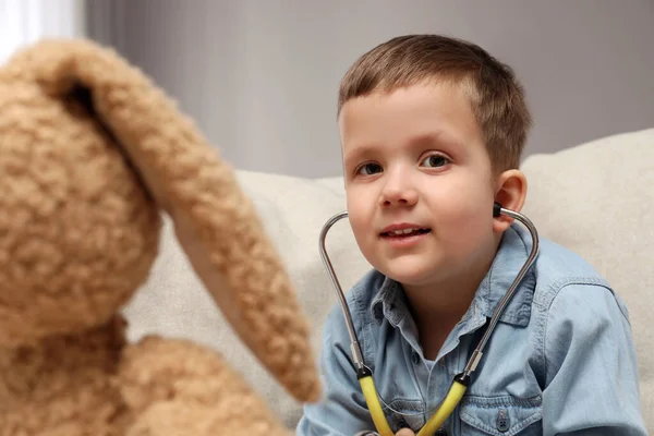 可爱的小男孩在室内玩听诊器和玩具兔子 未来的儿科医师 — 图库照片