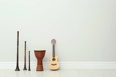 Ukulele, klasik bryolka ve beyaz duvarın yanında el davulu, yazı için yer. Müzik aletleri