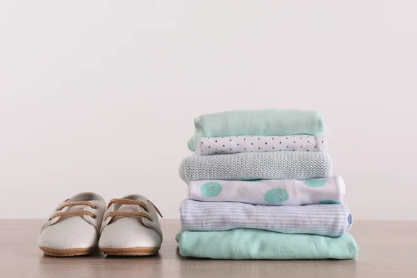 Stapelweise Babykleidung Und Schuhe Auf Holztisch Vor Weißem Hintergrund Platz — Stockfoto