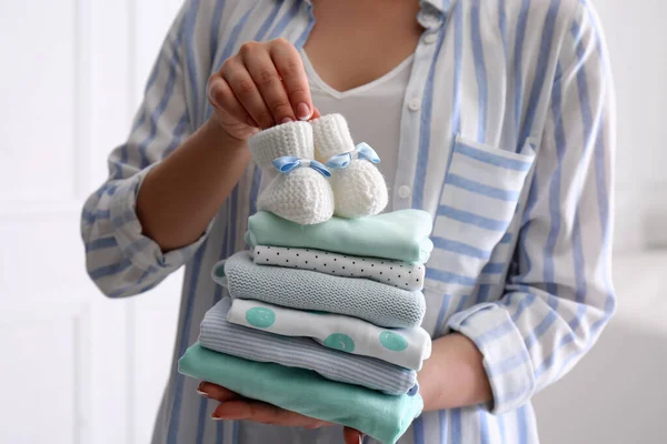 Vrouw Houden Stapel Van Baby Kleding Kleine Laarsjes Binnen Close — Stockfoto