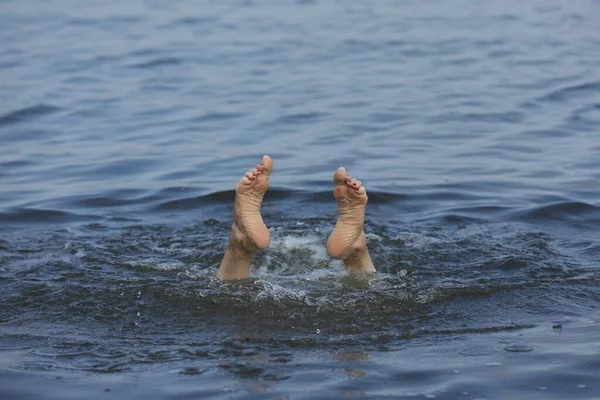 Woman drowning in sea, closeup of feet
