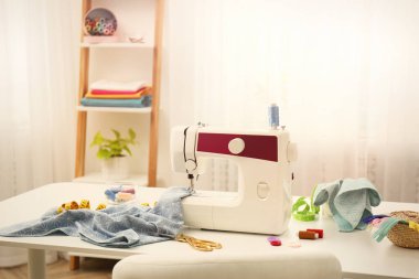 Modern dikiş makinesi, kumaş ve aksesuarlar masa içinde.