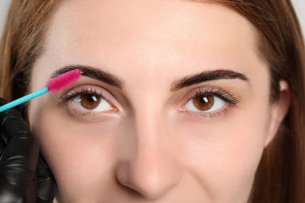 Beautician brushing woman\'s eyebrows after tinting, closeup