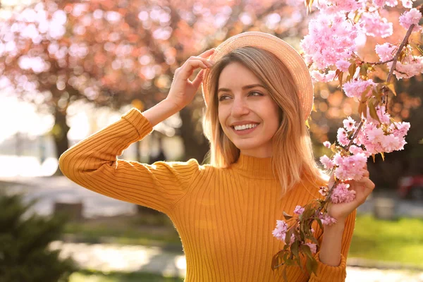 公園の桜の花の近くにスタイリッシュな服を着て若い女性 ファッショナブルな春の表情 — ストック写真