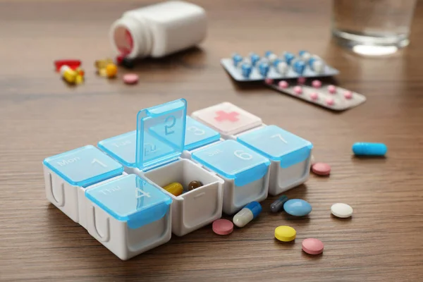 木製のテーブルの上に異なる薬とプラスチックボックス — ストック写真