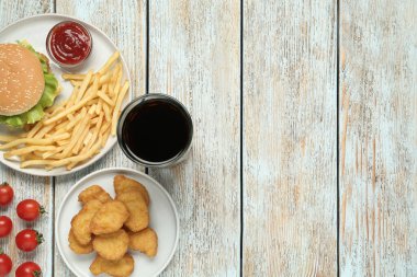 Düz kompozisyon ve beyaz ahşap masada lezzetli fast food menüsü. Metin için boşluk