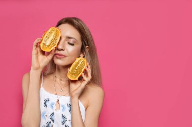 Pembe arka planda taze kiwanosu olan genç bir kadın, mesaj için yer var. Egzotik meyve