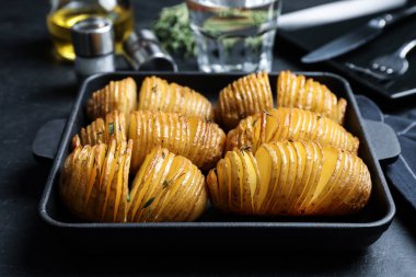 Lezzetli ev yapımı Hasselback patatesleri siyah masada tavada.