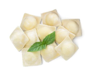 Beyaz arka planda pişmemiş ravioli ve fesleğen.