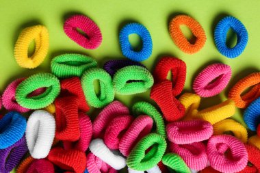 Açık yeşil arka planda farklı renkli saç bağları, düz yatış