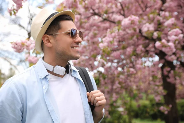 春の日に開花公園でヘッドフォンと幸せな男性観光客 — ストック写真