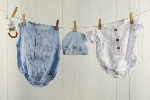 Bebek Kıyafetleri Aksesuarlar Beyaz Ahşap Duvarın Yanındaki Çamaşır Ipinde Asılı — Stok fotoğraf