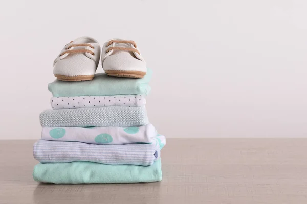 Stapelweise Babykleidung Und Schuhe Auf Holztisch Vor Weißem Hintergrund Platz — Stockfoto