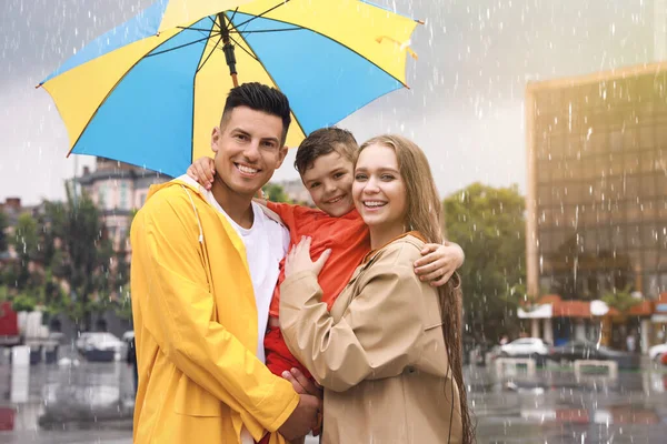 街の通りで雨の下を歩く傘を持つ幸せな家族 — ストック写真