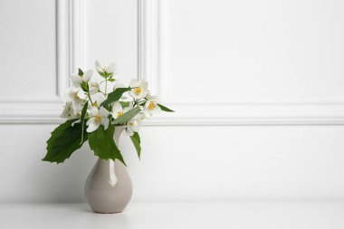 Beyaz masada vazoda taze yasemin çiçekleri olan güzel bir buket.
